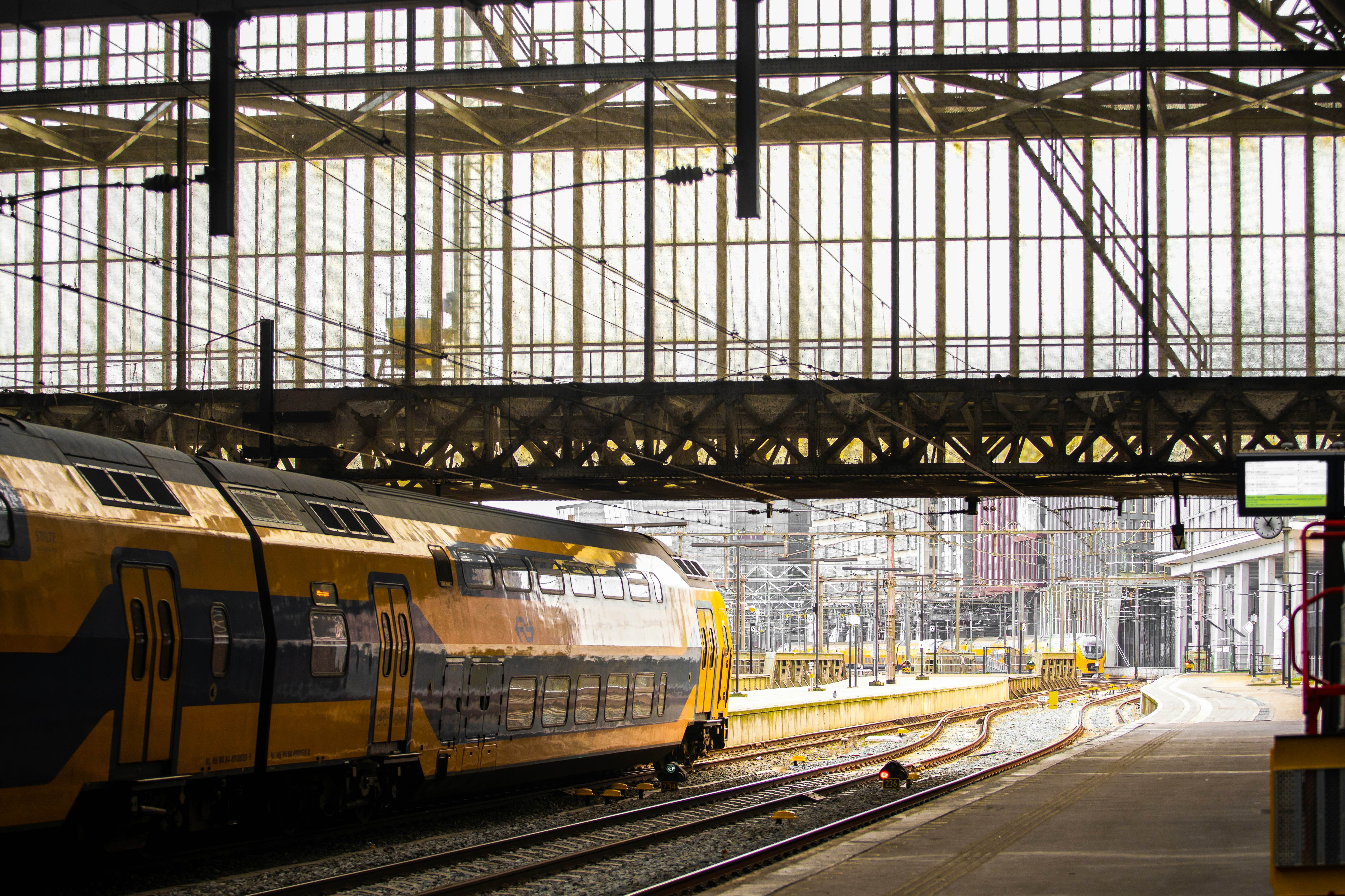 NS treinen op overdekt stationsperron met industriële staalconstructie, professionele werkomgeving voor werkplekbeveiliging